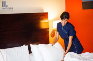 Maid making a bed in a hotel room